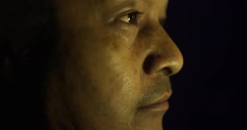 Vista de perfil de una persona bajo una iluminación tenue que transmite pensamientos y emociones profundos