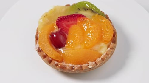 Pasteles giratorios con frutas sobre fondo blanco.