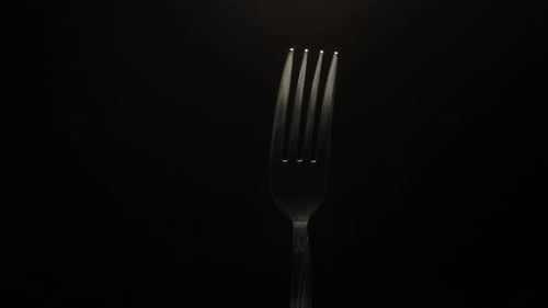 The fork is close-up, rotating on a black background.