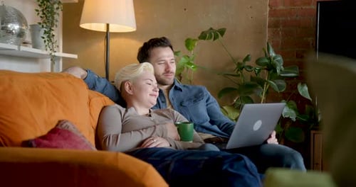 Relaxed Couple on Couch Watching Laptop at Home