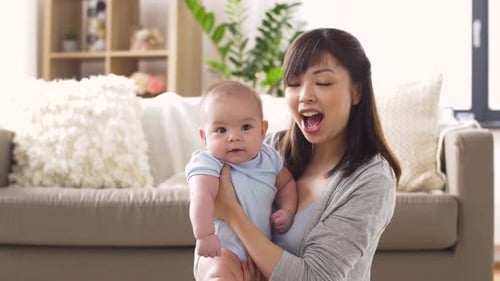 Loving Mother Holding Cute Baby in Living Room