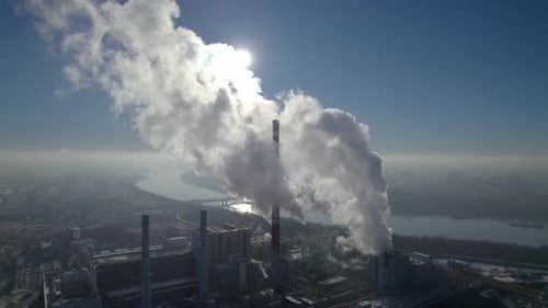 Aerial orbit over a coal-fired heating power station with thick white smoke coming from the chimney,