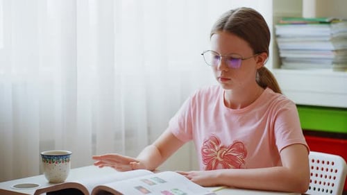 Teen with Glasses Reads and Does Homework