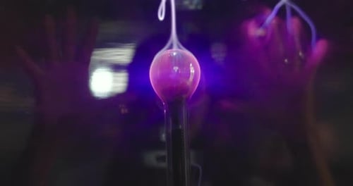 Nahaufnahme einer Hand, die eine Teslaspule berührt, die Elektrizität enthält. Konzept von: Magie, Macht, Spiel