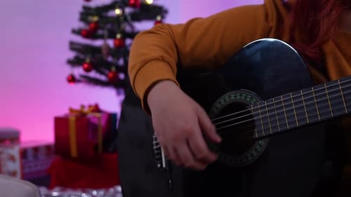 Person Playing Guitar Near Christmas Tree With Gifts
