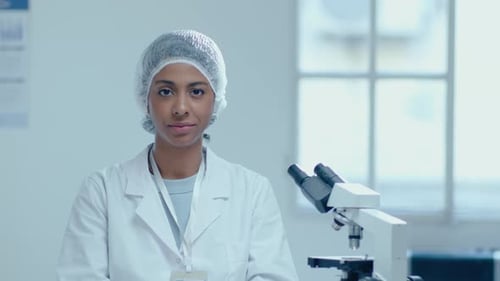 Scientist Next to Microscope in Bright Lab
