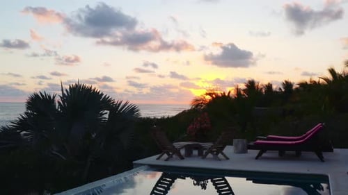 Drone flies over luxurious pool in private beachside ocean front villa, and up towards the beach at