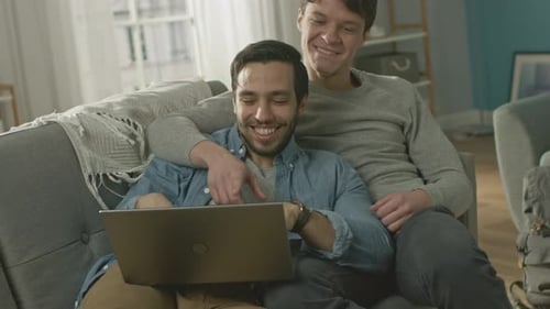 Affectionate Men Relaxing on Sofa with Laptop
