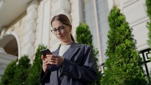 Professional Young Woman Using Smartphone Outside Elegant Building
