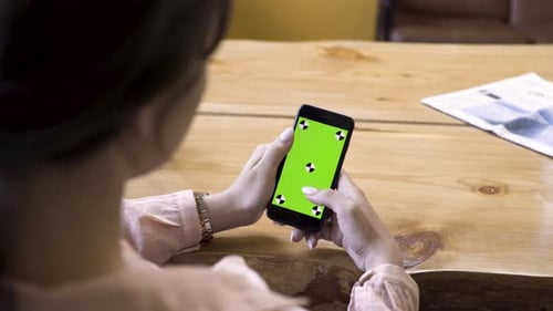 Woman Using Smartphone with Green Screen in Office