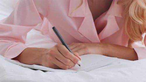 Blonde Woman Writing in a Notebook at Home During a Relaxing Morning