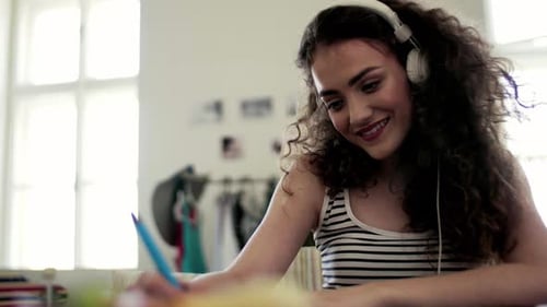 Teenage Girl Listens to Music and Writes