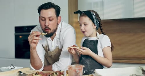 Father and Daughter Enjoying Homemade Pizza in Kitchen