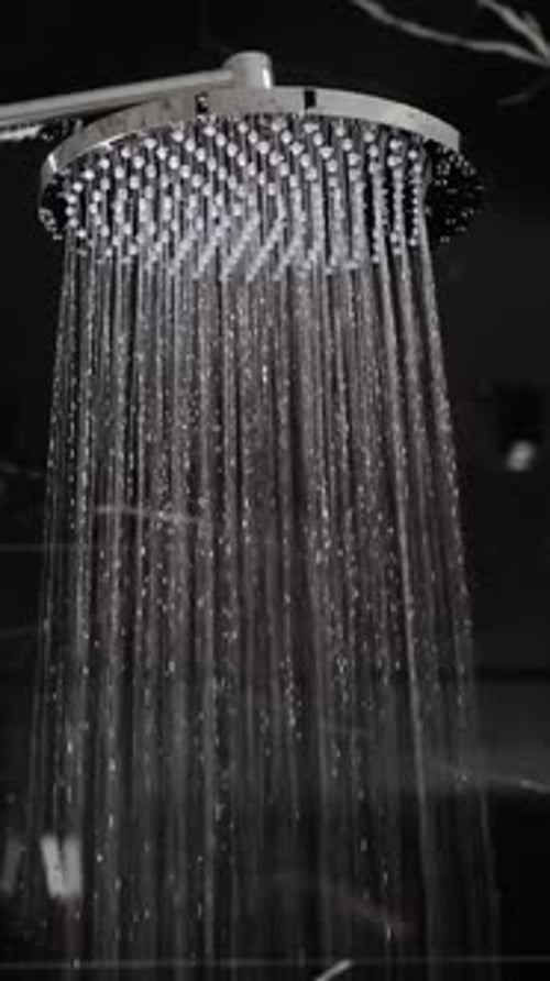 Jets of water flow from the round shower head. Elite plumbing and comfort vertical