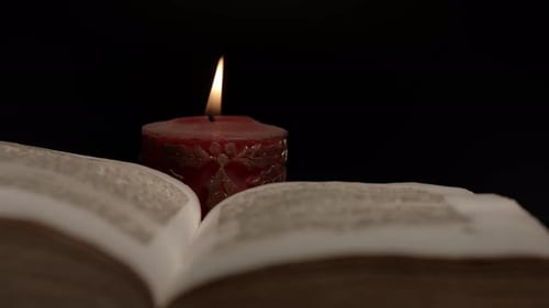 Nahaufnahme eines offenen Buches, umgeben von Kerzenschein