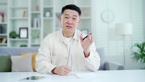 Webcam view. Confident asian businessman or teacher talking on video call sitting in home office