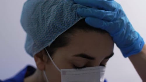 Tired Healthcare Worker Removing Surgical Cap and Mask