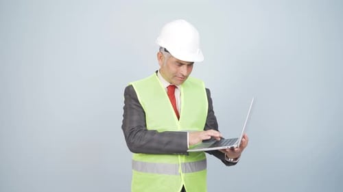 Engineer holding laptop laughing at camera.