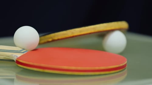 Camera moving around the table tennis set. Ping pong balls, paddles.