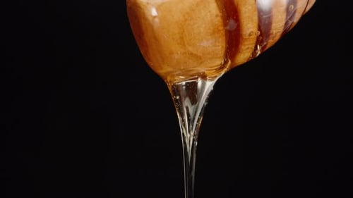 Delicious Honey Pours from Dipper into a Bowl