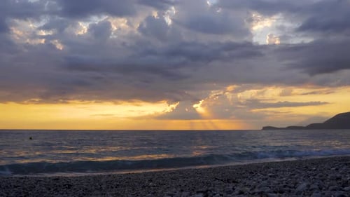 Time lapse of dark clouds moving over sea and beach at beautiful sunset with yellow sky