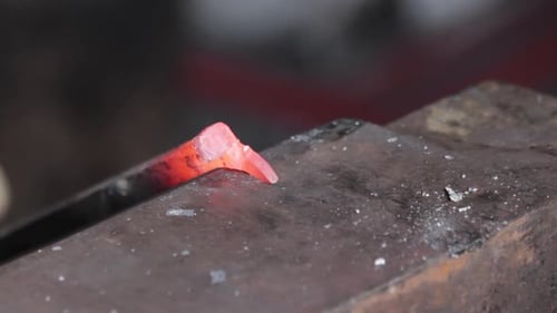 Close up of blacksmith hammering out a shape from metal