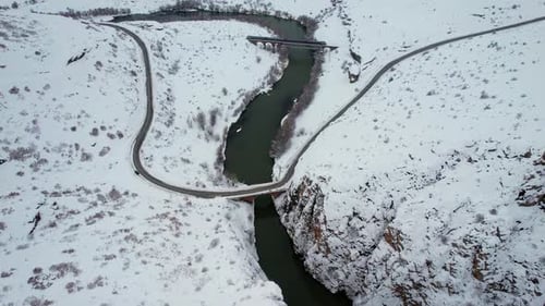 Train Crossing Bridge Over Snowy River in Winter Landscape