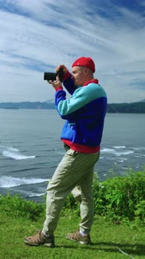 Man Taking Photo on Scenic Coastline