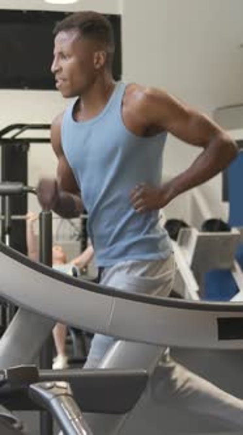 Muscular Black Man Running on Treadmill in Gym