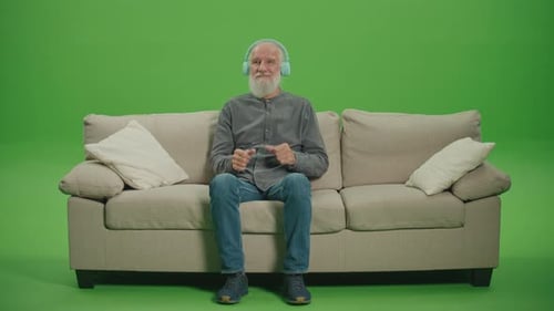 Green Screen An Old Man with a Gray Beard Listens to Music on Headphones