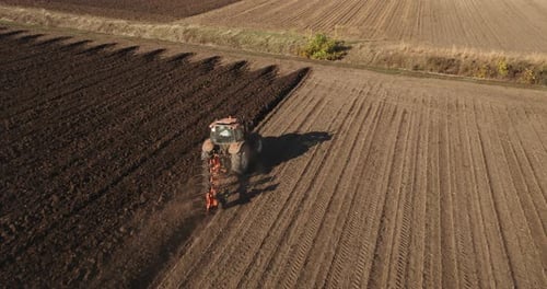 Tractor Tilling Soil on Vast Farmland, Aerial View