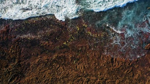 Prístina, rocosa, volcánica, árida costa y agua oceánica turquesa con olas blancas espumosas