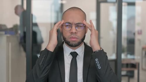 Stressed Man Massaging Temples at Office