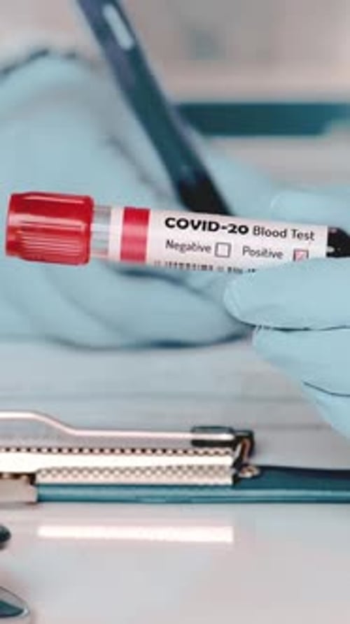 Gloved Hand Holds Blood Sample and Medical Form