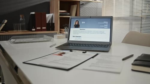 Large Table with Laptop Displaying Applicants CV, Paper Forms, Leather Notebook