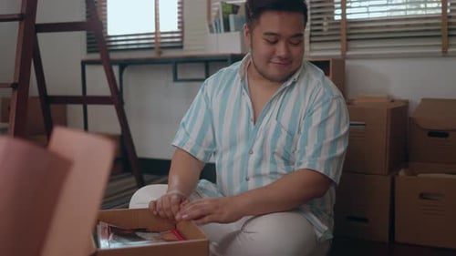 Thoughtful Young Adult Packing Memories in Moving Box