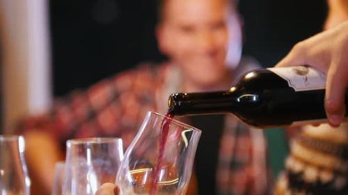 Ein Mann gießt Wein in Gläser, Leute reden in der
