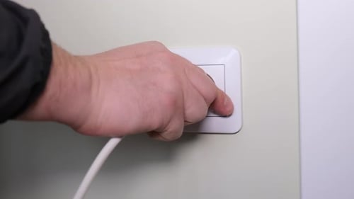 Plugging White Power Cord into Electrical Outlet