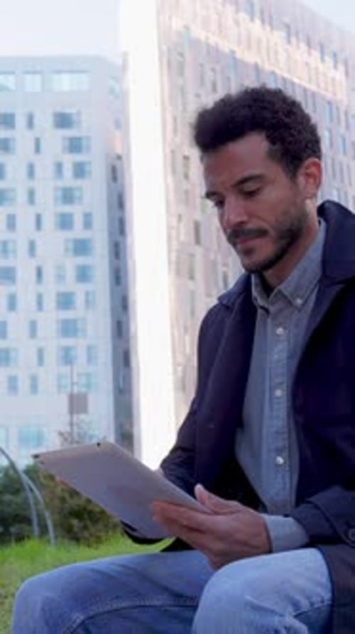 Jeune homme d'affaires latino-américain adulte travaillant sur une tablette à City Park
