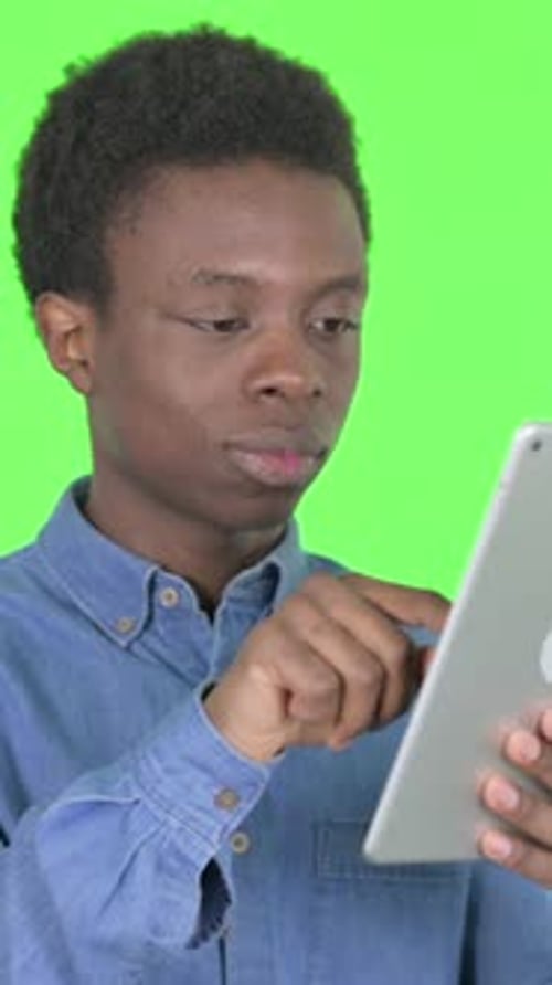 Young African Man Celebrating Success on Tablet on Green Background, Vertical Video