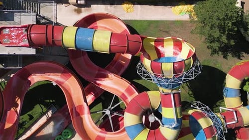 Aerial View of Colorful Twisting Water Slides with People Riding Inflatable Tubes at a Water Park
