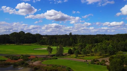Aerial view of Golfers teeing off onto golf course fairway under beautiful blue sky