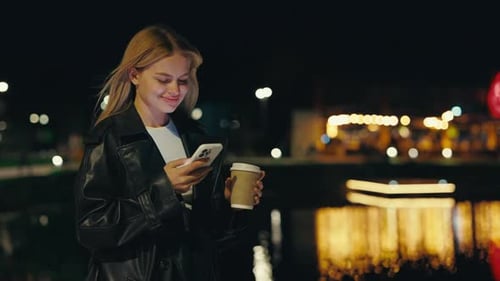 Young Woman Using Phone at Night in City