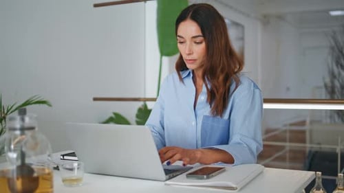 Attractive Woman Browsing Laptop in Contemporary Office Focused Project Manager