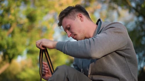 Jeune homme en sweat à capuche gris tenant une sangle à l'extérieur dans la nature