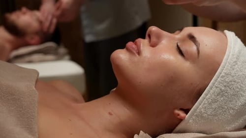 Couple Receiving Relaxing Face Massage at Tranquil Spa Retreat with Warm Towels Soothing Touch and