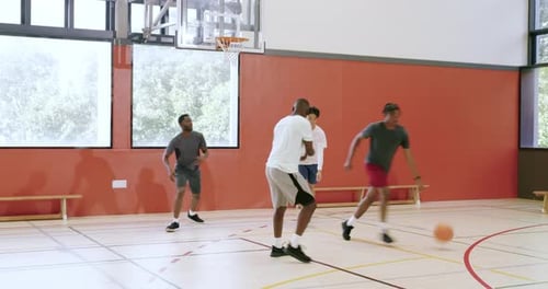 Basket-ball dribble sous un cerceau de gymnase, divers amis masculins faisant semblant de bouger, conduisant