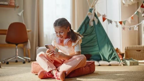 Smiling Girl Using Smartphone in Child's Bedroom