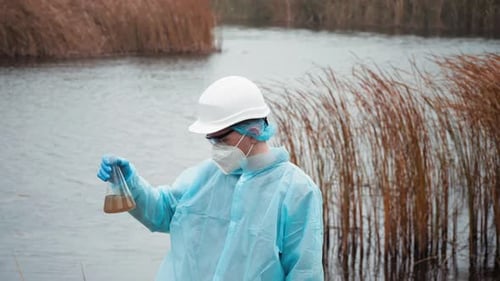 Scientist Analyzing Water Sample Next to Lake