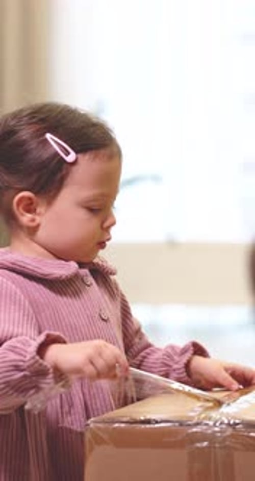 Cute Little Child Girl Opens Parcel at Home
